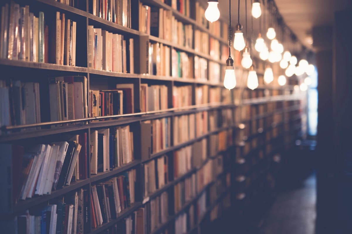 Stacked notebooks and reading light on a wooden shelf